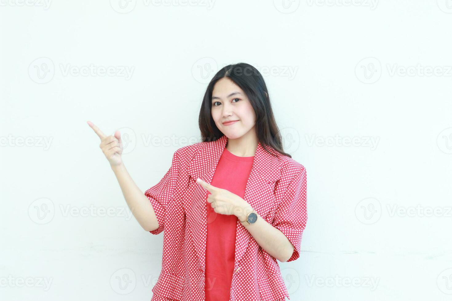 portrait of beautiful asian woman wearing red outfit pointing to the side for copy space with smiling gesture photo