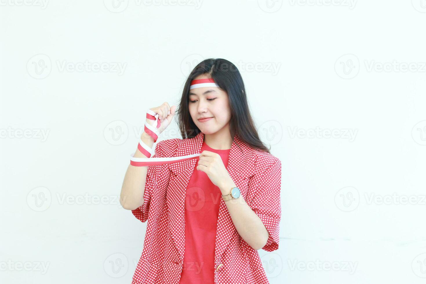 portrait of an asian woman wearing a red outfit tying her hands with a flag ribbon in the context of independence day of Indonesia photo