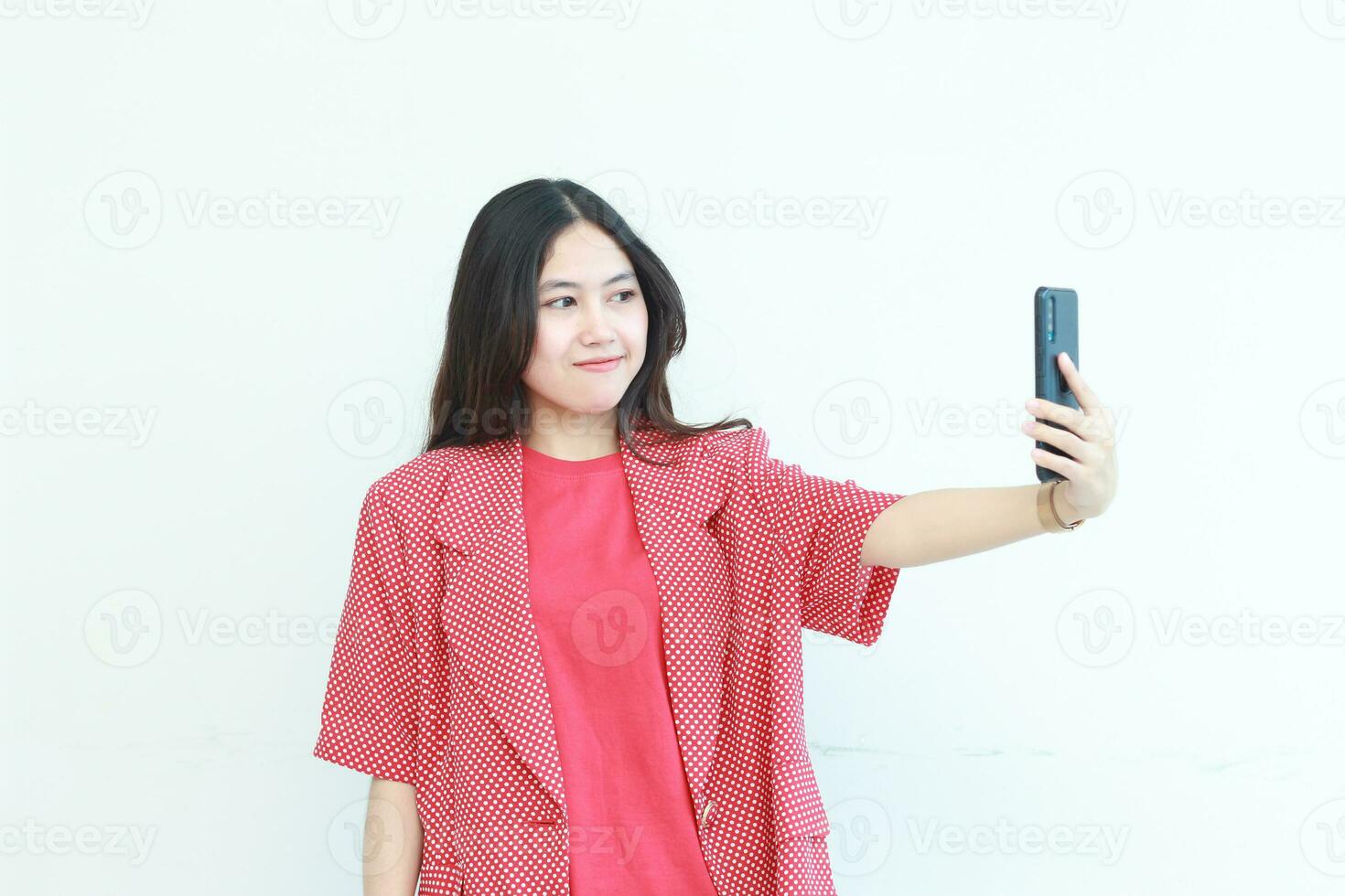 portrait of beautiful asian woman wearing red outfit looking at mobile phone with happy expression photo