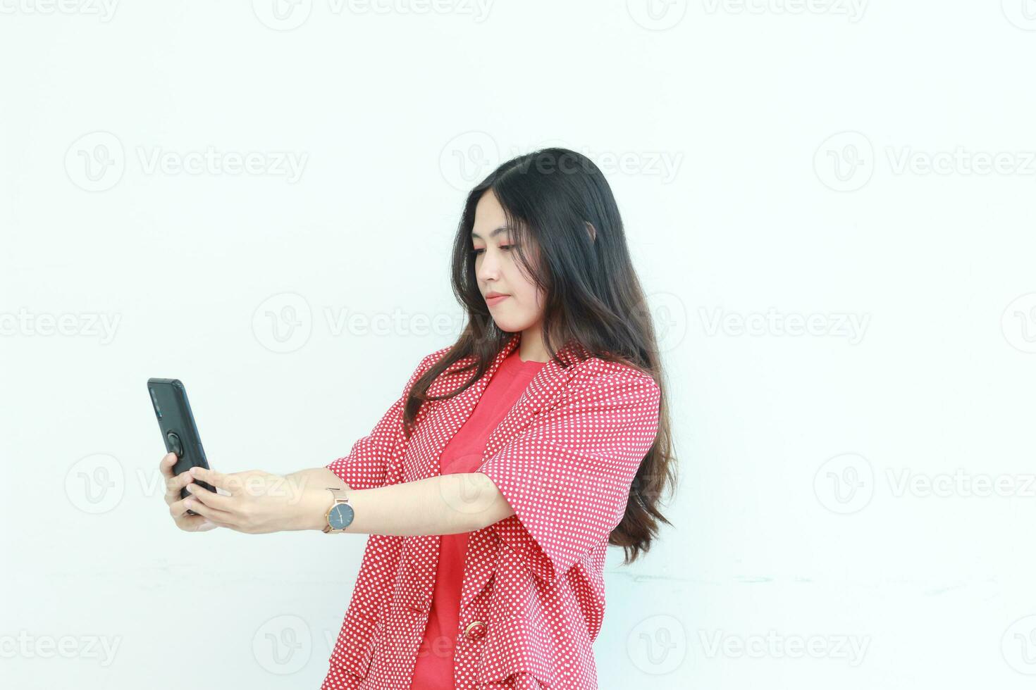 portrait of beautiful asian woman wearing red outfit looking at mobile phone with happy expression photo