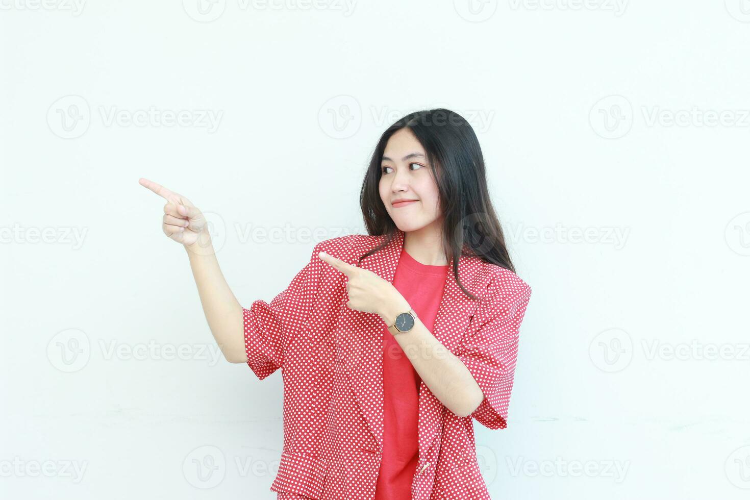 portrait of beautiful asian woman wearing red outfit pointing to the side for copy space photo