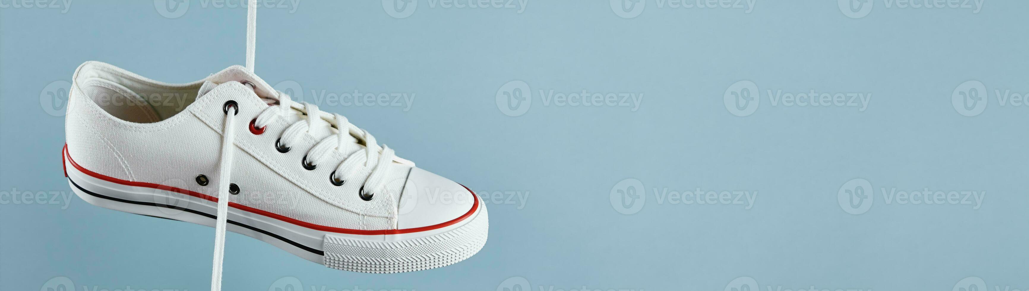 White casual sneakers on blue background, creative minimalism photo