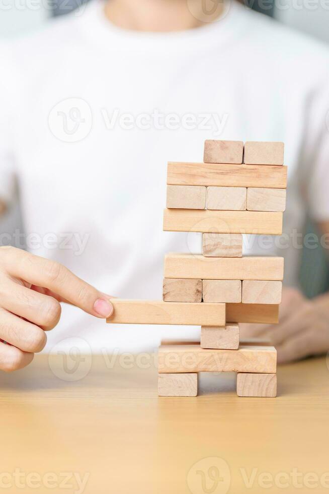 hand pulling wooden block tower on table. Business planning, Risk Management, Solution, leader, strategy, Crisis, falling Business, and Economic recession concept photo