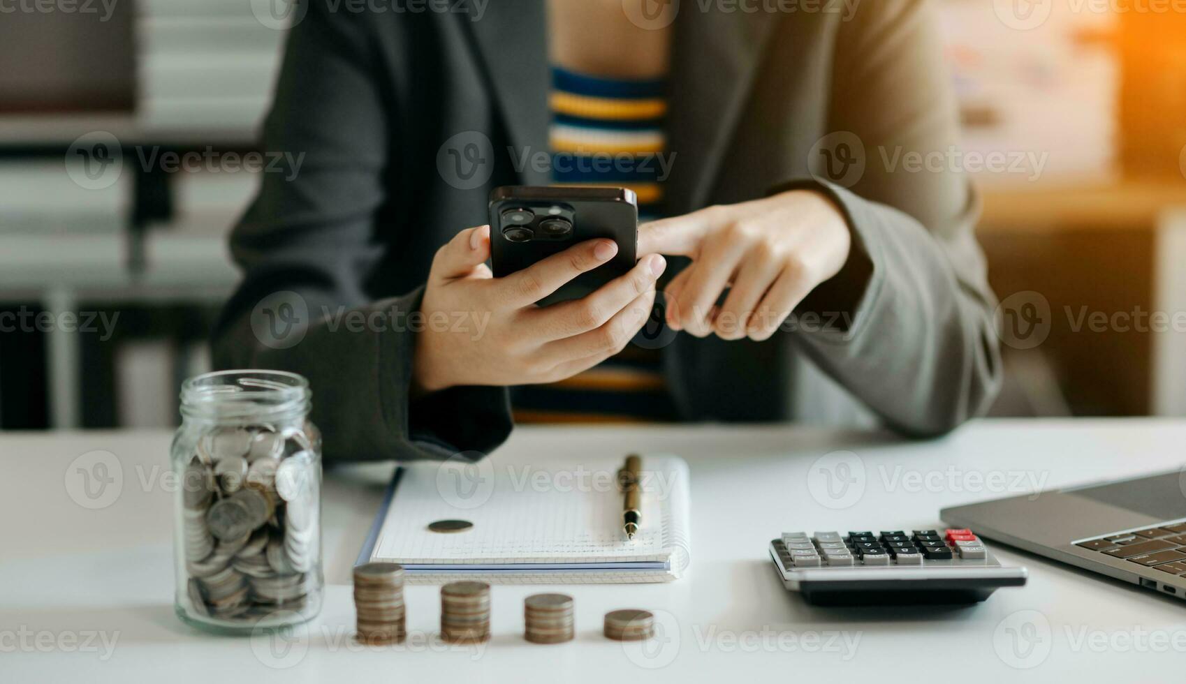 Business accountant working on desk using mobile phone and calculator to calculate budget concept finance and accounting in morning light photo