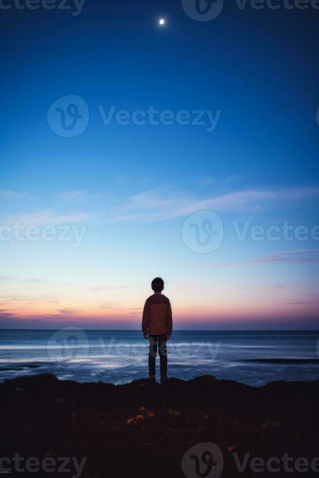 un niño mirando a el horizonte aislado en un oscuridad degradado antecedentes foto