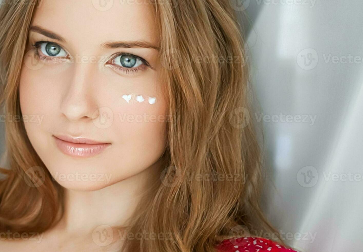 Beautiful woman with skincare cream on her face photo