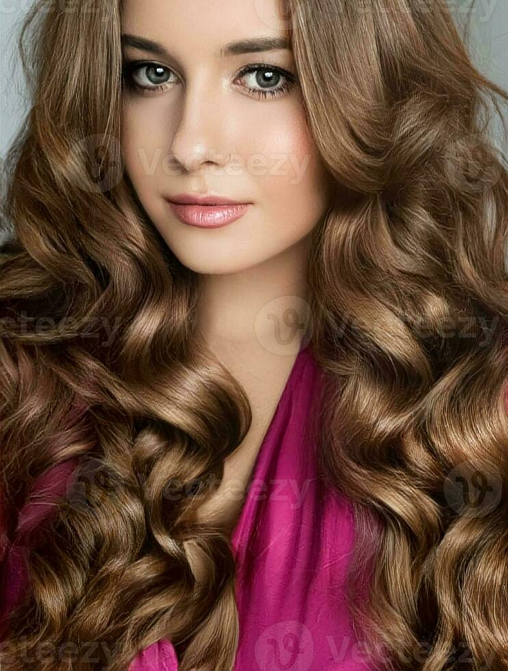 Beautiful woman with curly volume hairstyle, long luxurious hair and beauty make-up, glamorous look face portrait for luxury fashion and natural cosmetics photo