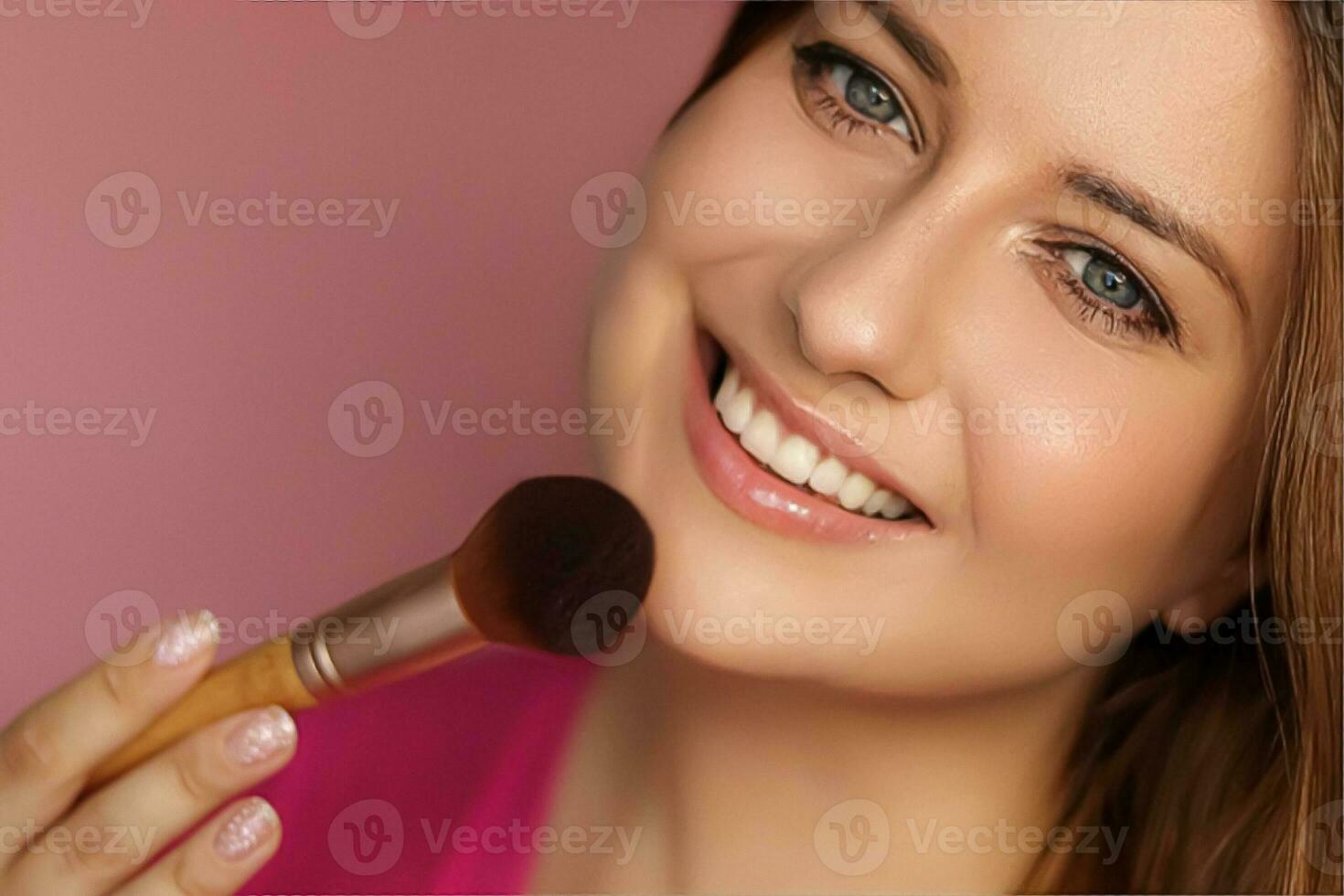 Beautiful young woman applying cosmetic powder product with make-up bamboo brush, beauty, makeup and skincare cosmetics model face portrait on pink background photo