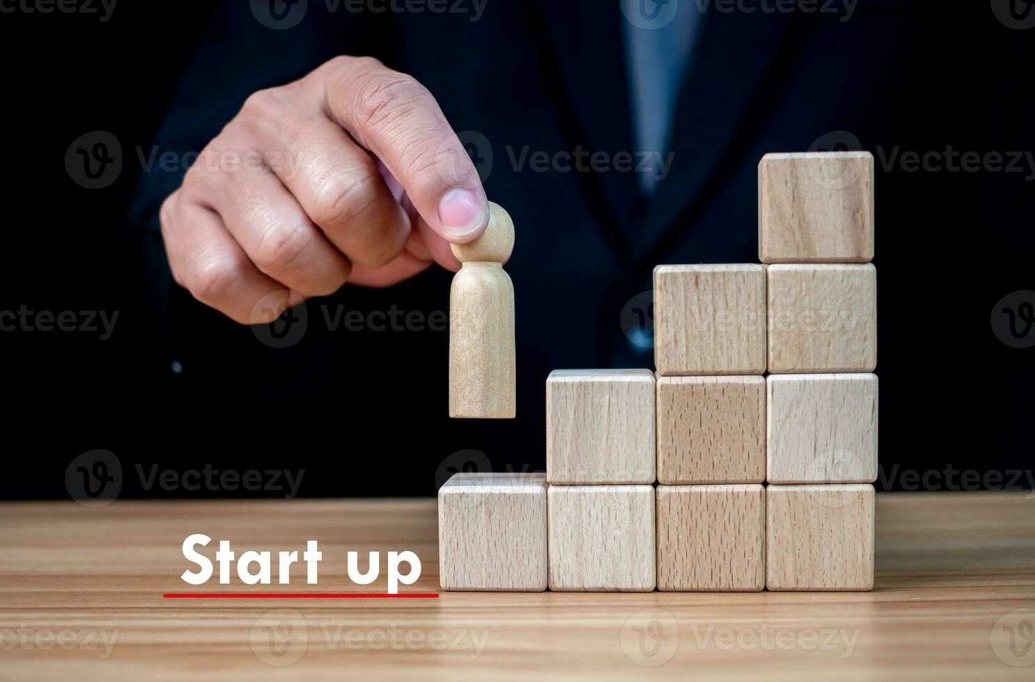 Businessman holding a wooden doll on the first step of the stairs. represents the start of a business. Startup concept. Business concept. photo