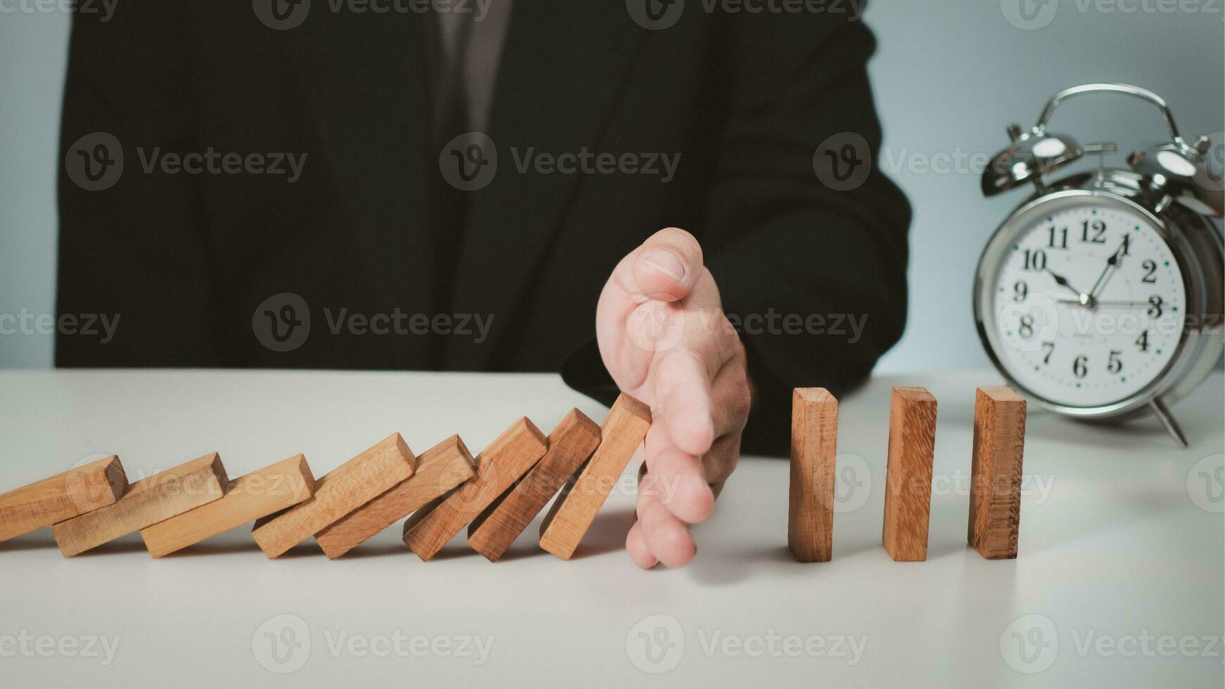 Risk management concept. Businessman hand stopping dominoes effect for business. photo