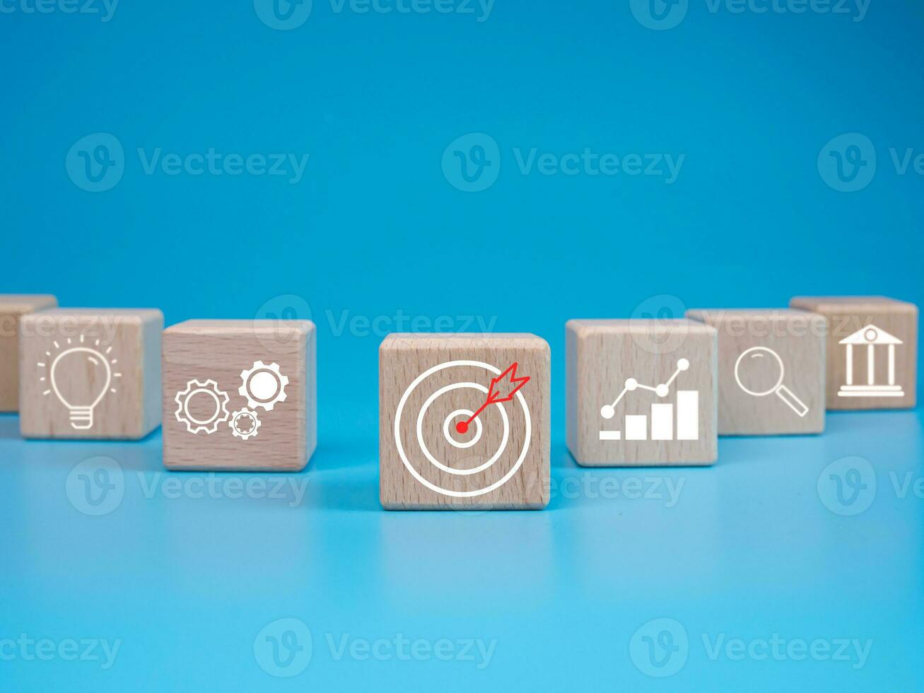 wooden block which prints a target icon and business symbol on light blue background. Business goals and objectives concept. business competition. business target concept. photo