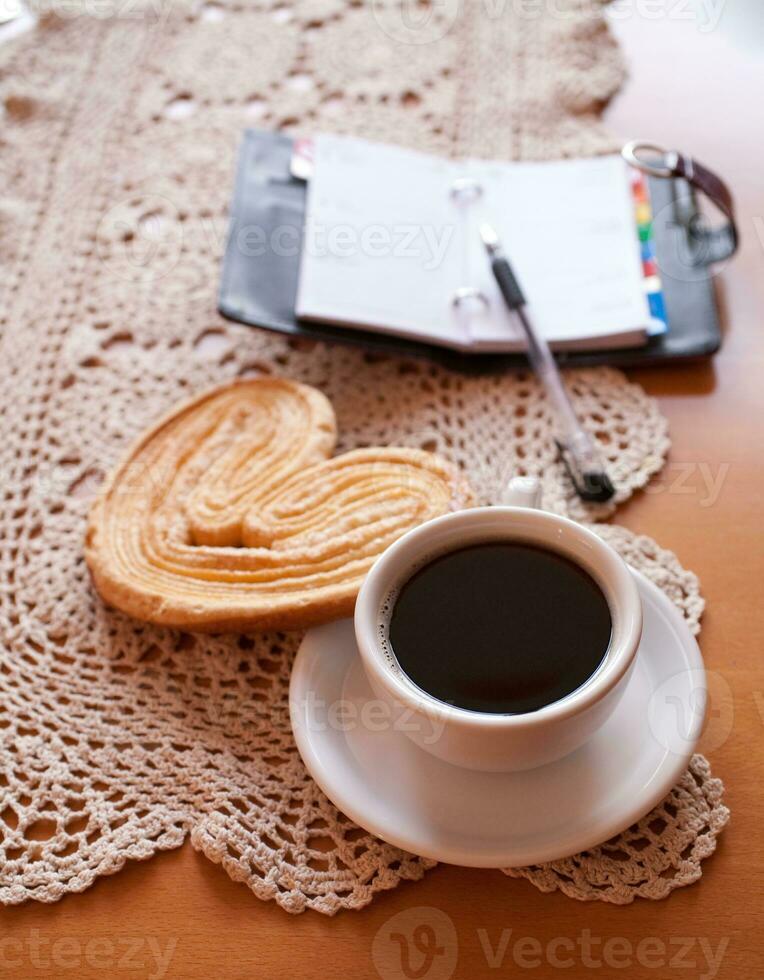 white cup of black coffee and a sweet buttery cookie on the table photo