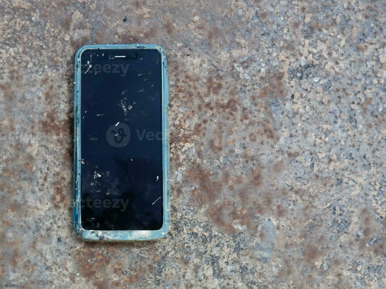old mobile phone with broken screen on the concrete floor photo