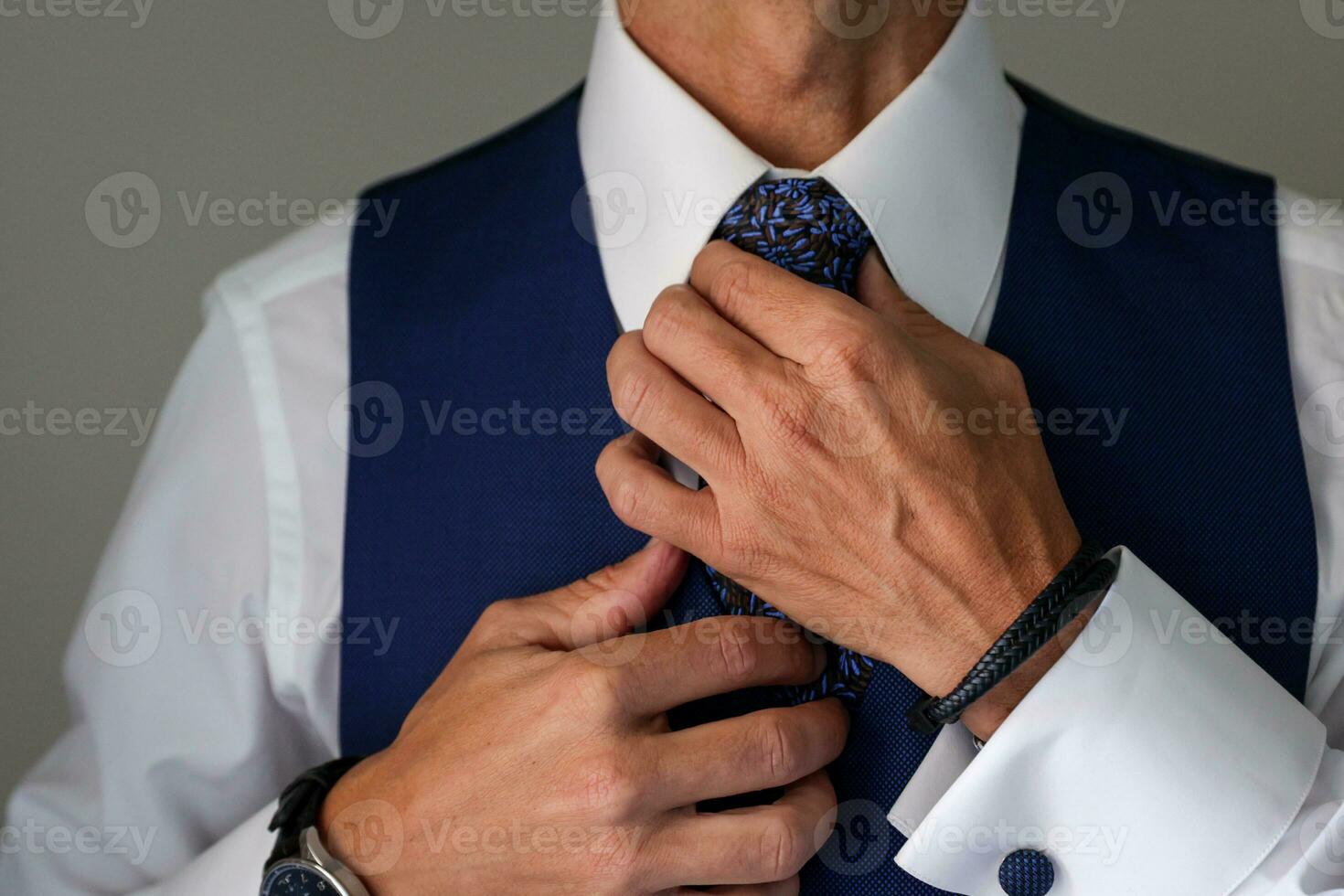 groom getting ready for his wedding and tightening his tie photo