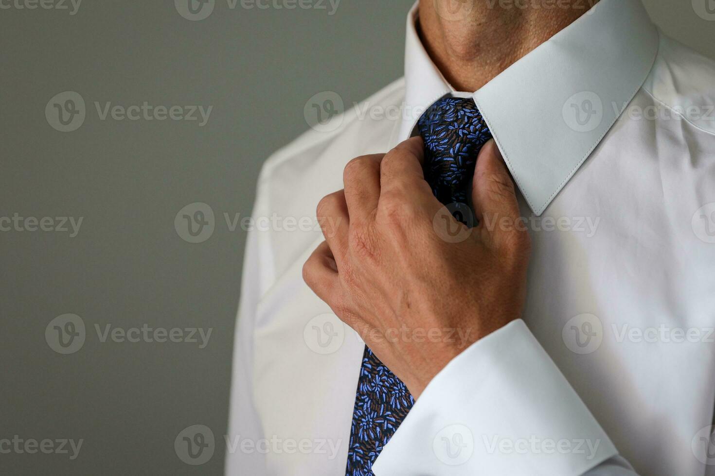 groom getting ready for his wedding and tightening his tie photo