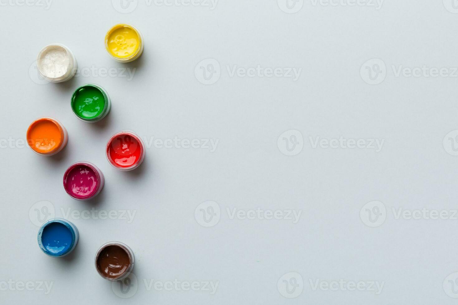 jars with gouache of different colors on Colored background. hobby painting. Top view with empty space. workplace for creativity. home teaching concept drawing photo