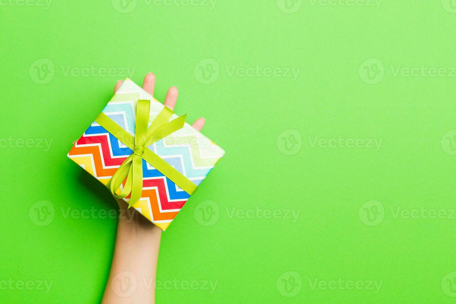Top view of female hands holding christmas or other holiday handmade present box package in the palms, flat lay table background with copy space photo