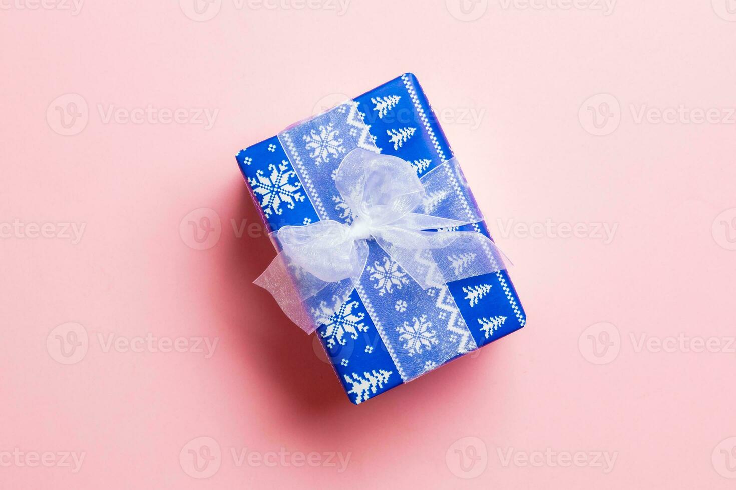 Top view Christmas present box with white bow on pink background with copy space photo