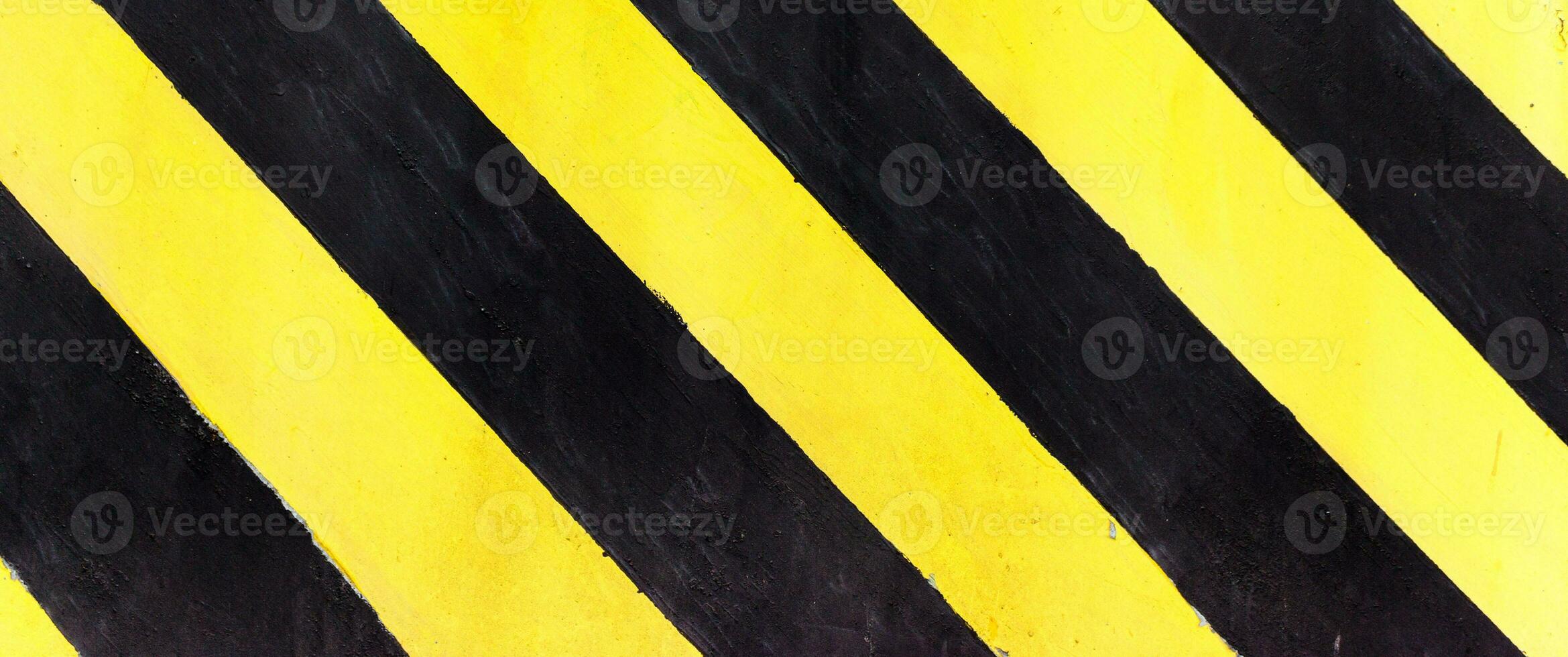 rayas de seguridad en el sitio de construcción, negro y amarillo bajo el signo de construcción sobre una textura gruesa, vista superior foto