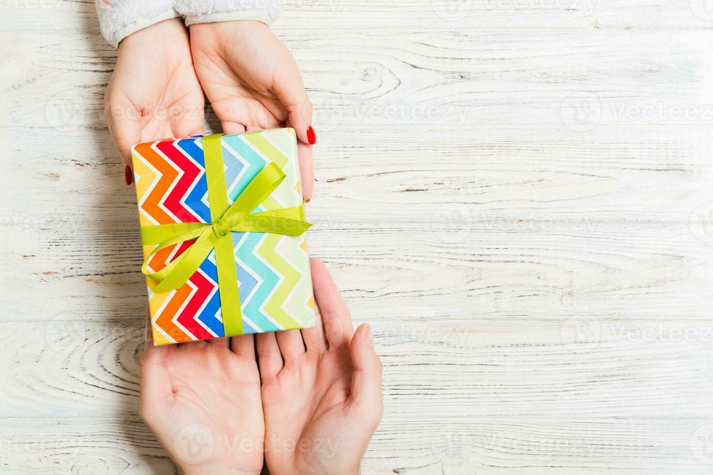 Top view of giving and receiving a present on wooden background. A man and a woman holding gift in hands. Festive concept with copy space photo
