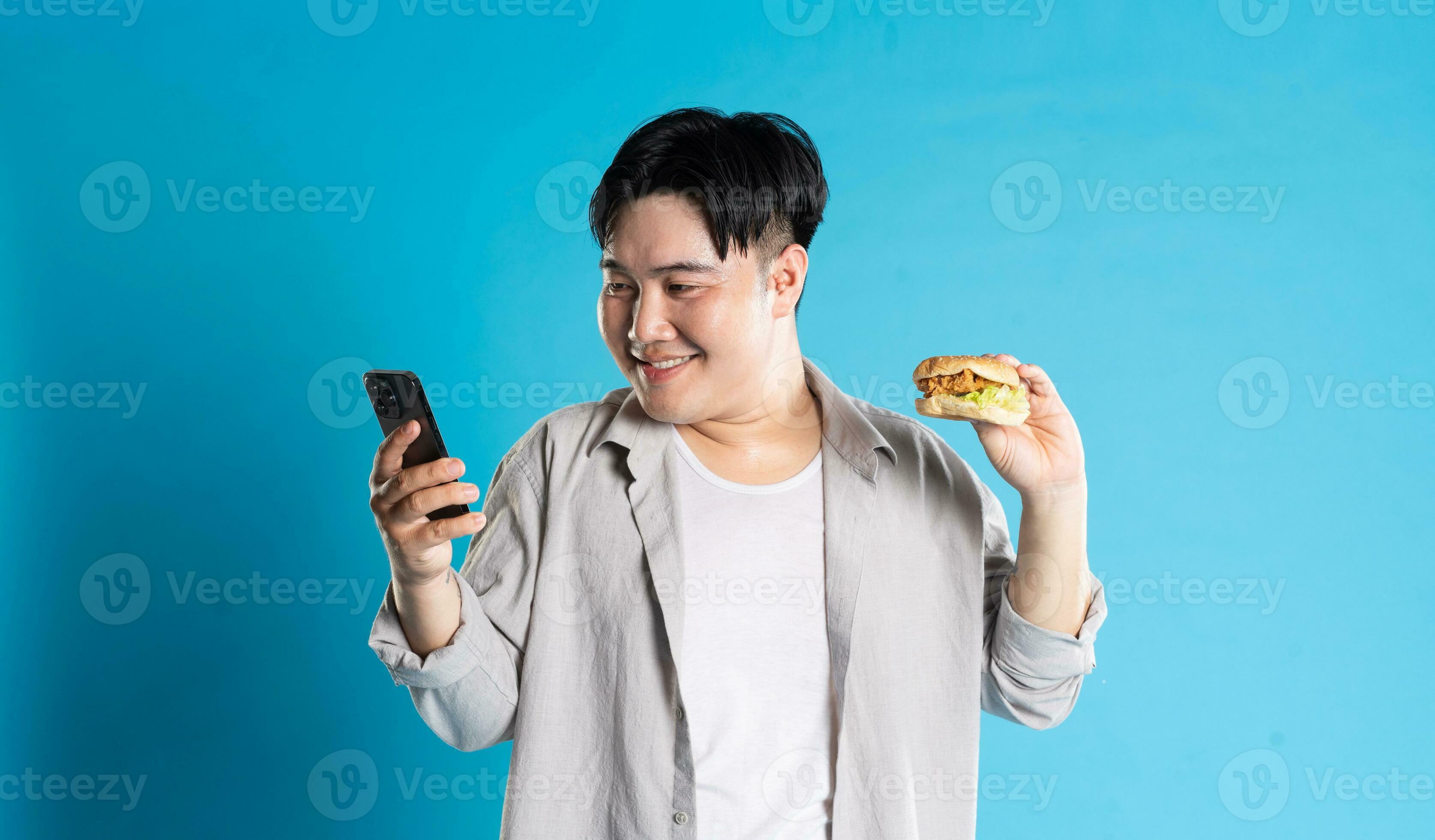 Portrait of asian man eating fast food on blue background 29335142