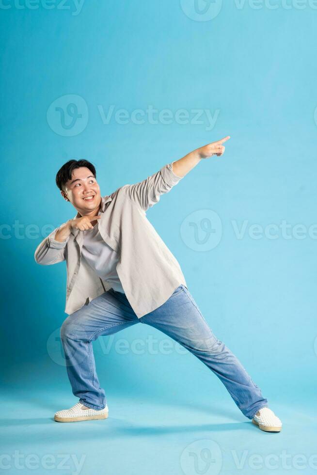 Full body image of Asian man posing on blue background photo