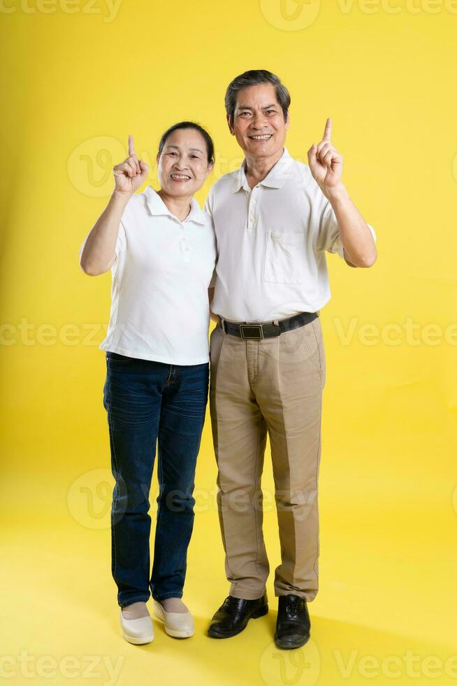 portrait of middle aged asian couple posing on yellow background photo