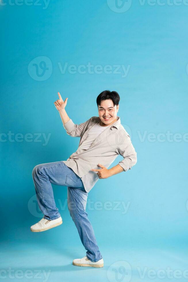 Full body image of Asian man posing on blue background photo