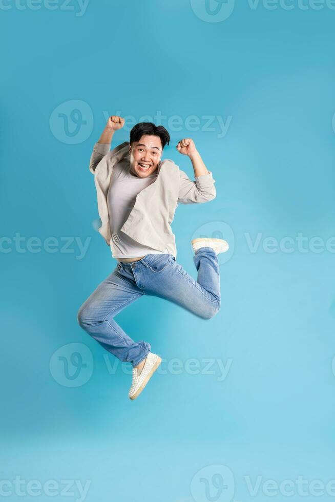 Full body image of Asian man posing on blue background photo