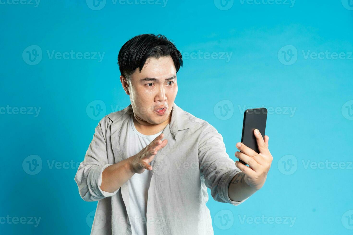 Image of Asian man using phone on blue background photo