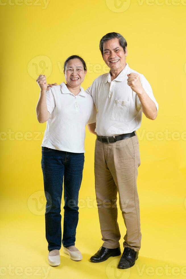 portrait of middle aged asian couple posing on yellow background photo