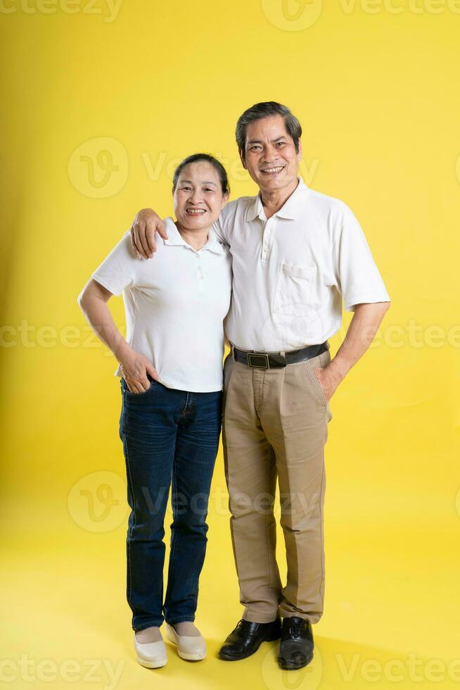 portrait of middle aged asian couple posing on yellow background photo