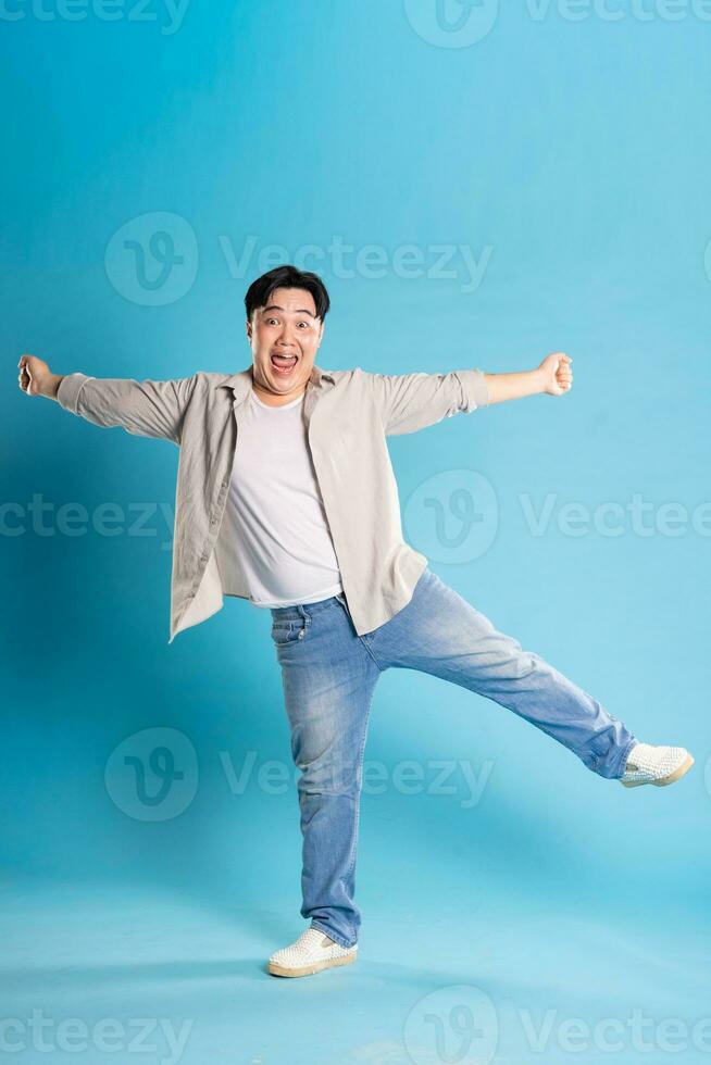 Full body image of Asian man posing on blue background photo