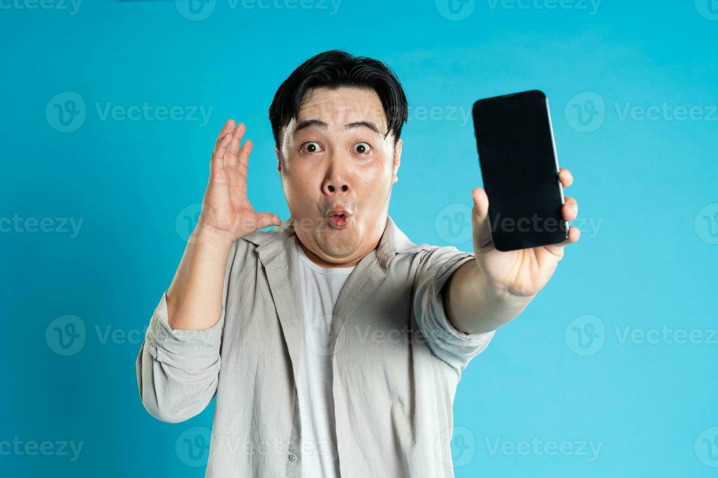 Image of Asian man using phone on blue background photo