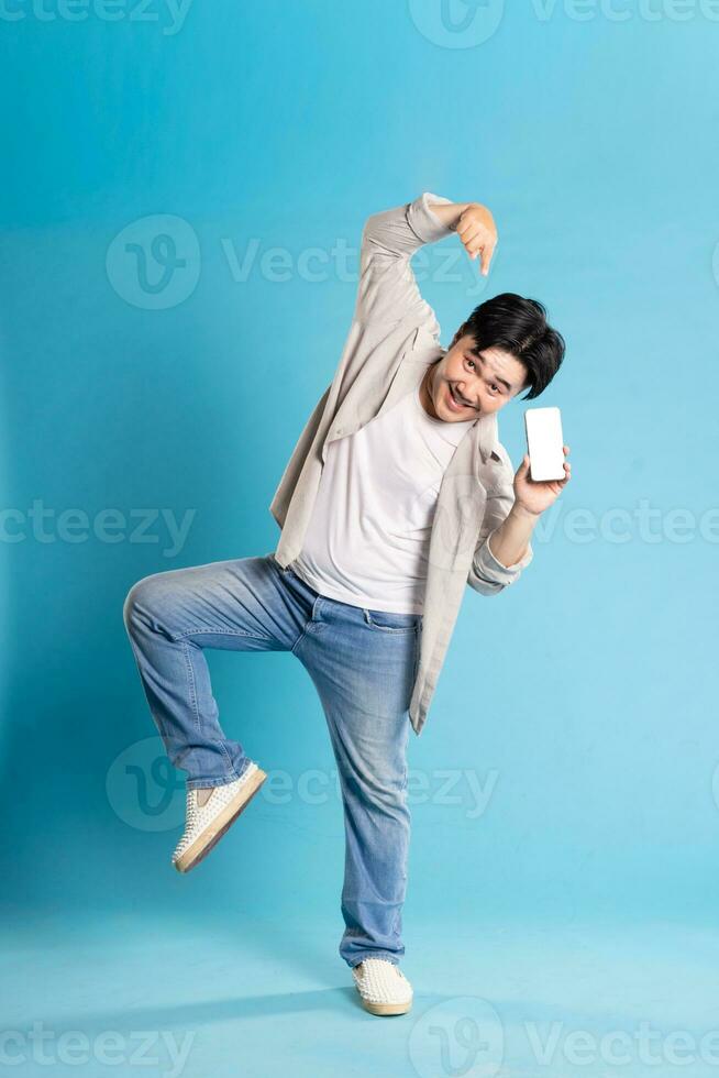 Full body image of Asian man posing on blue background photo