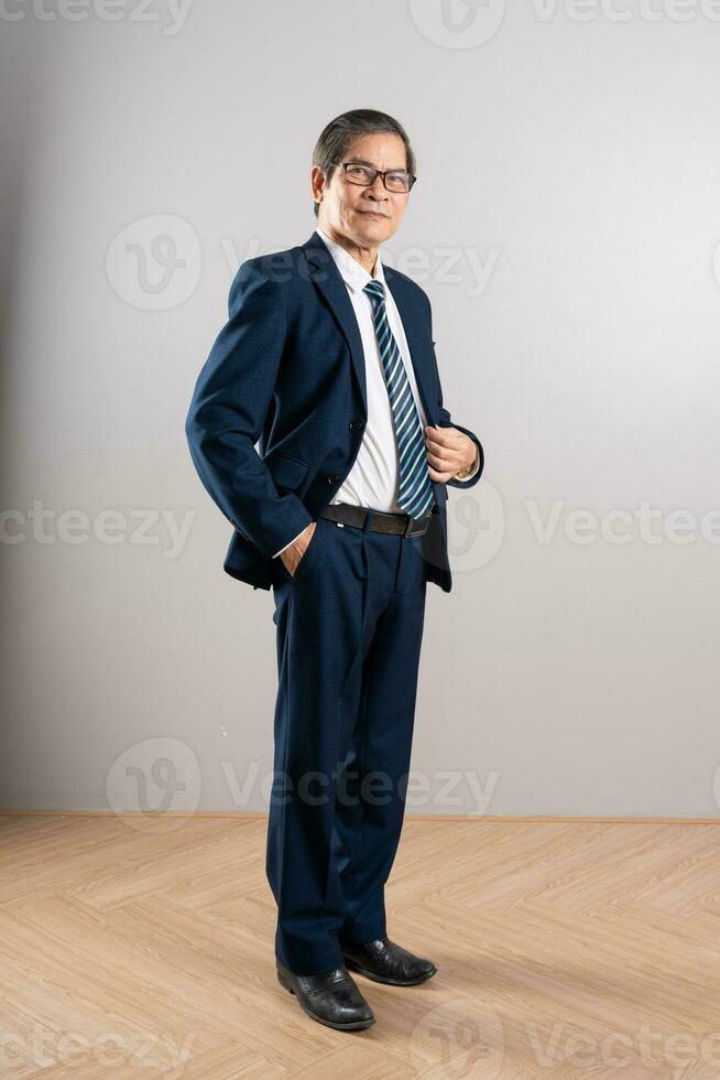 Portrait of an elderly Asian businessman, posing on a blue background photo