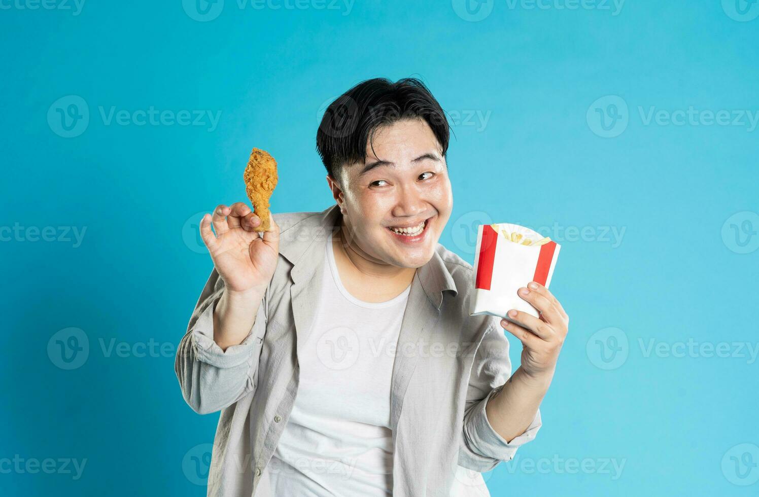 Portrait of asian man eating fast food on blue background photo