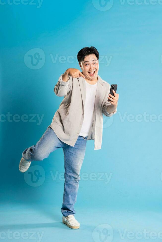 Full body image of Asian man posing on blue background photo