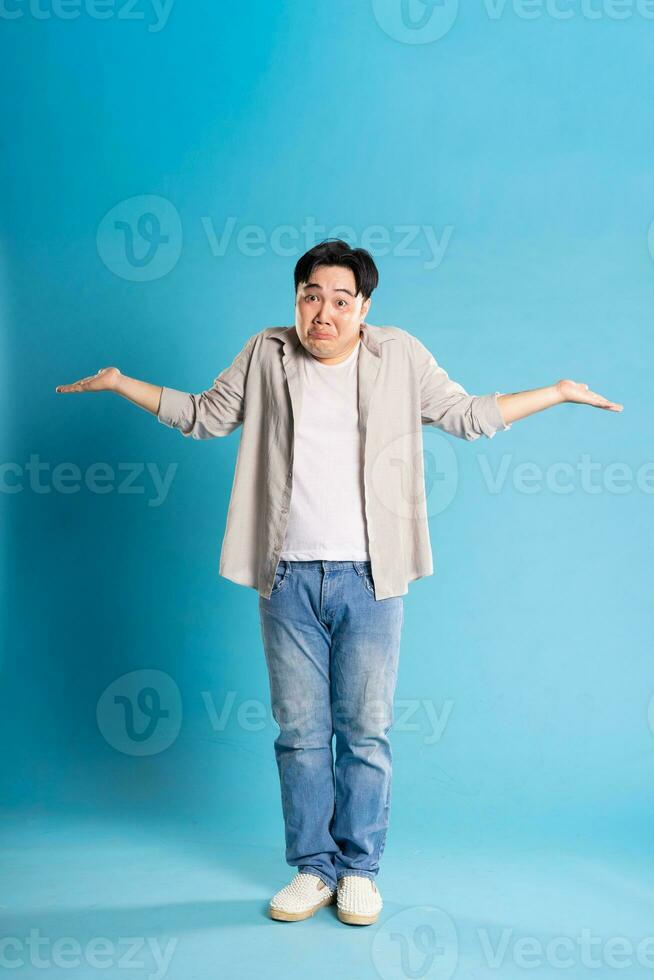 Full body image of Asian man posing on blue background photo