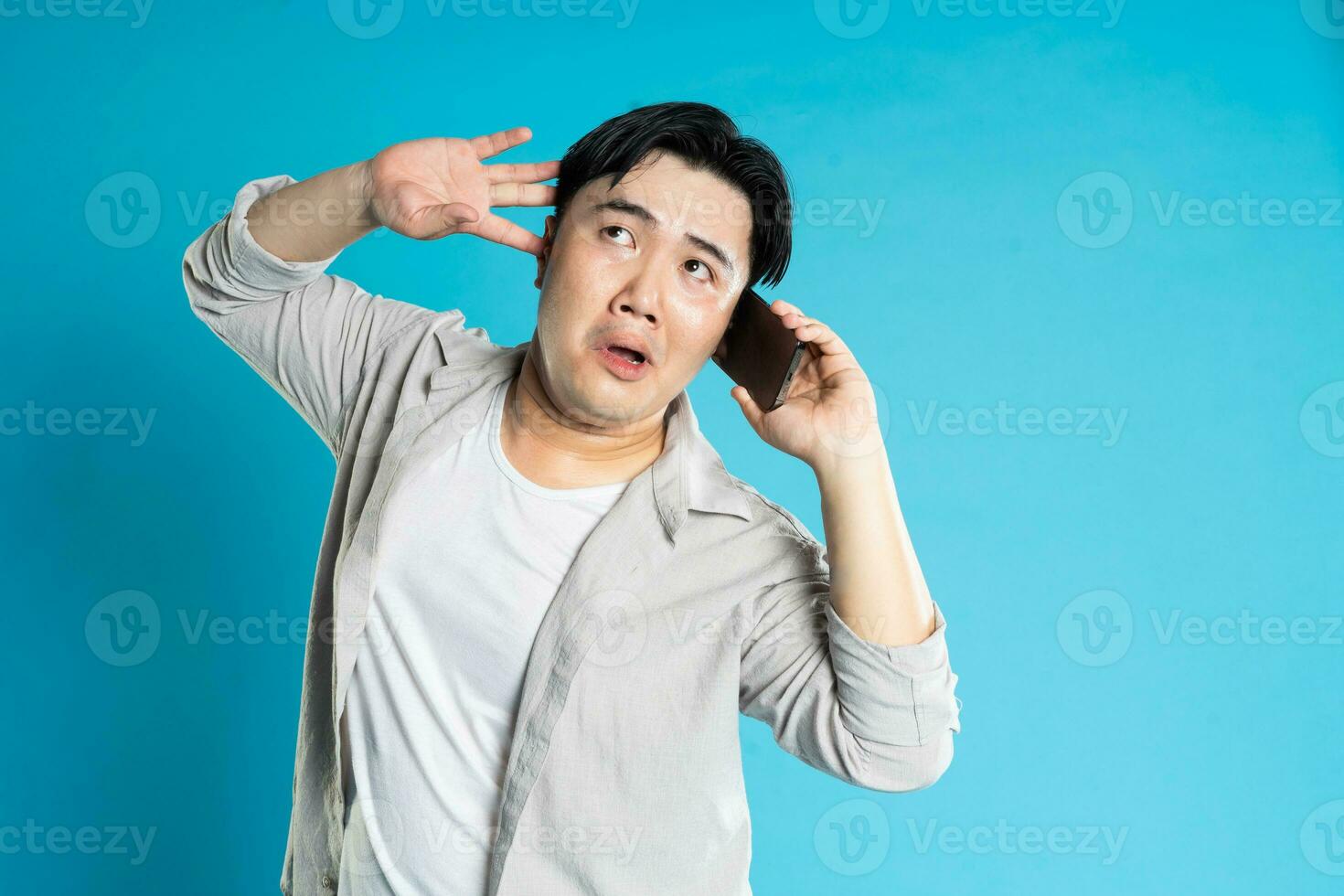 Image of Asian man using phone on blue background photo