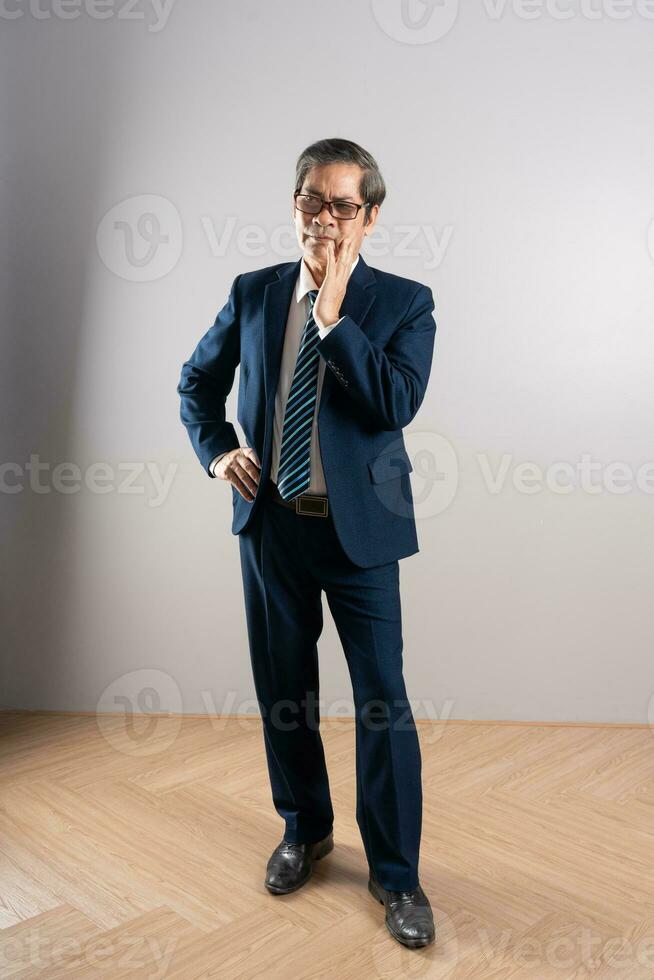 Portrait of an elderly Asian businessman, posing on a blue background photo