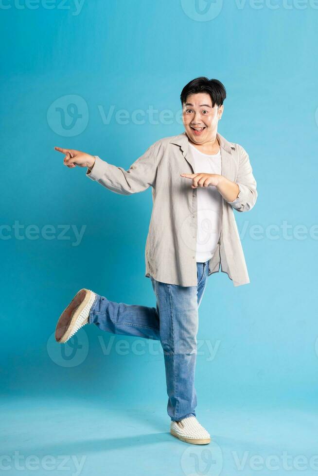 Full body image of Asian man posing on blue background photo