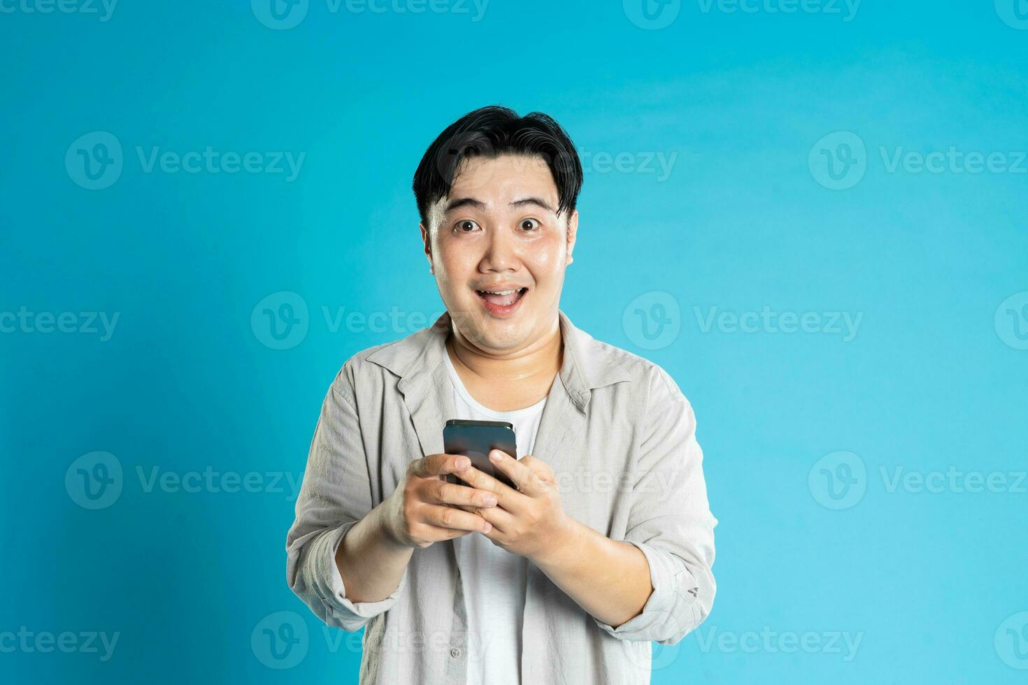 Image of Asian man using phone on blue background photo