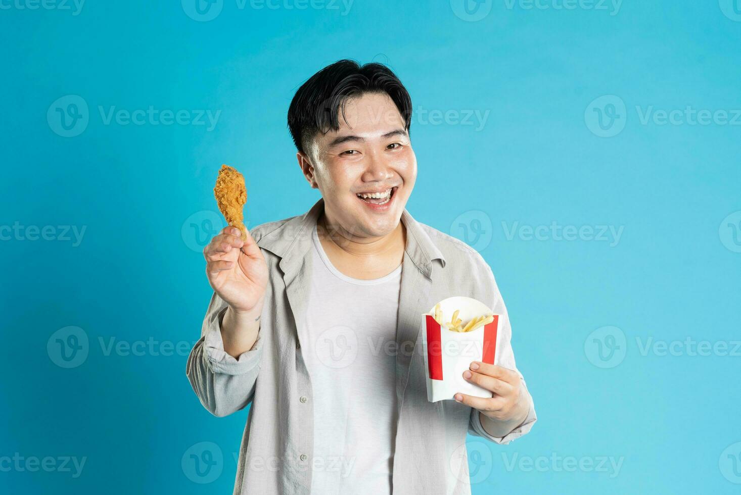 retrato de asiático hombre comiendo rápido comida en azul antecedentes foto