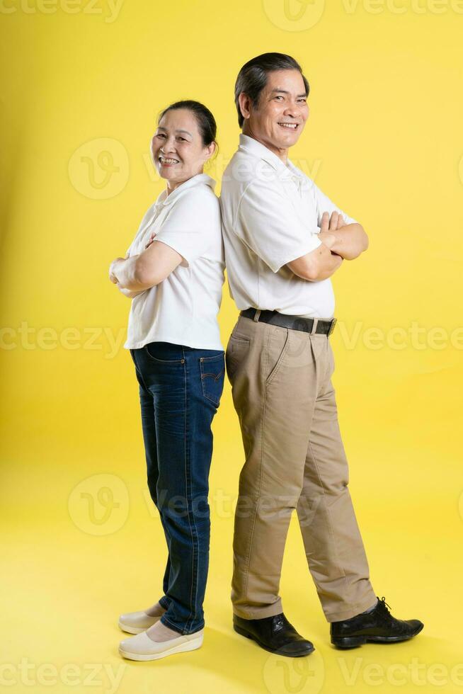 portrait of middle aged asian couple posing on yellow background photo