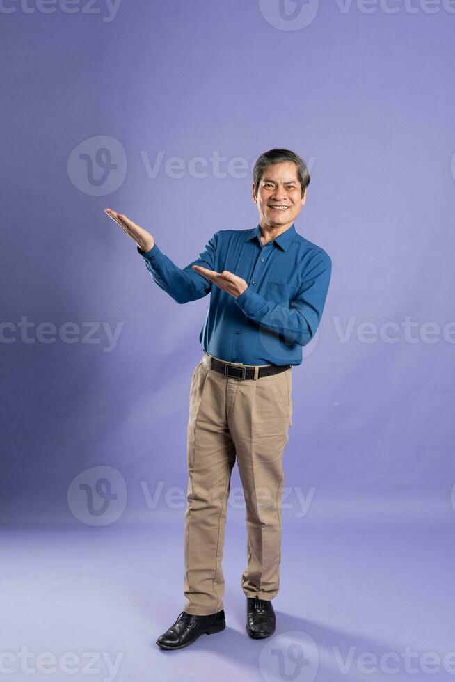 portrait of middle aged asian business man posing on purple background photo