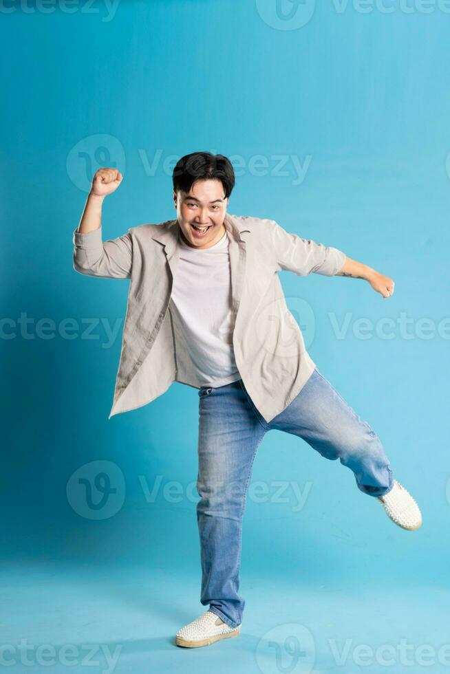 lleno cuerpo imagen de asiático hombre posando en azul antecedentes foto