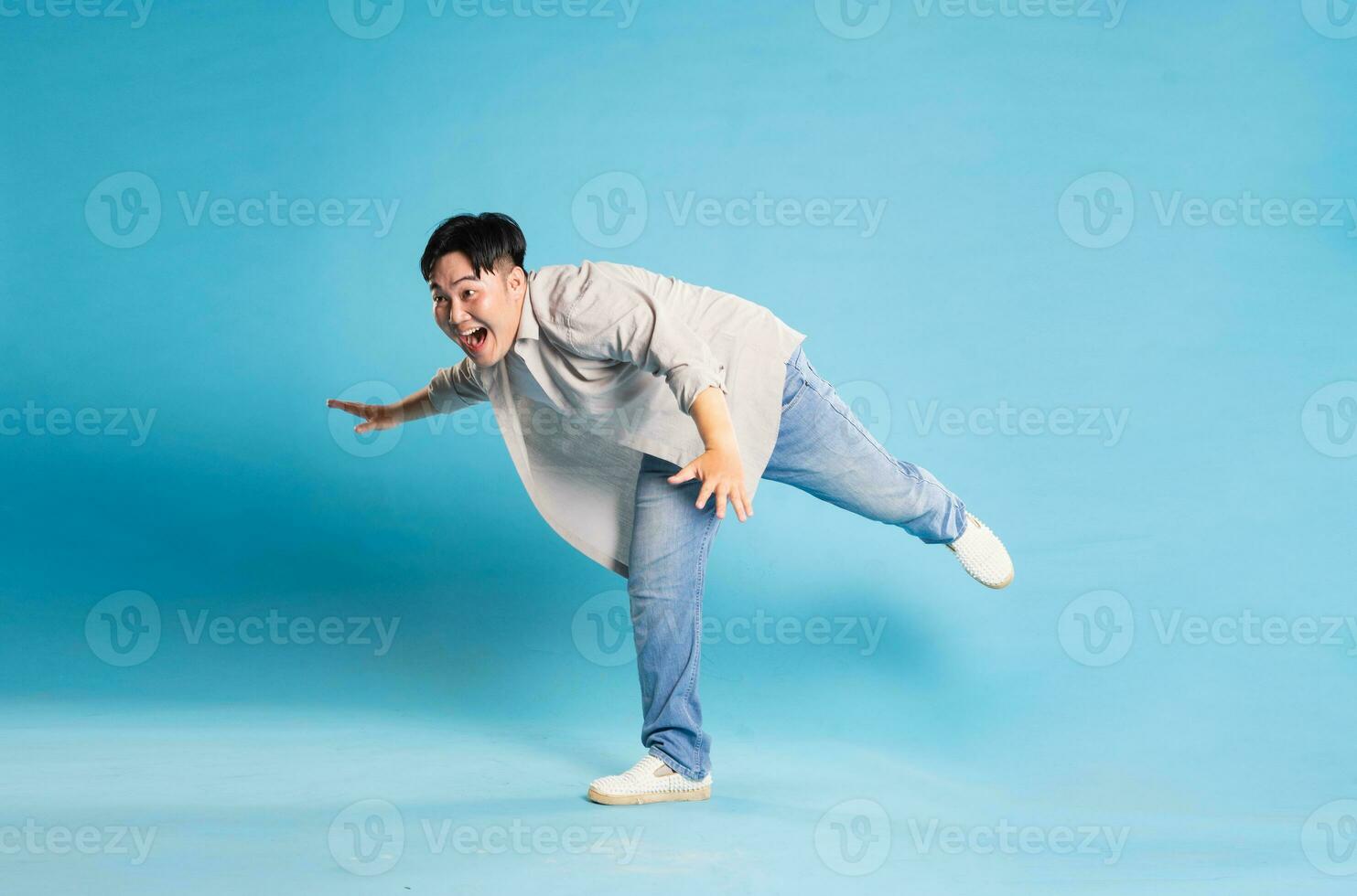 lleno cuerpo imagen de asiático hombre posando en azul antecedentes foto