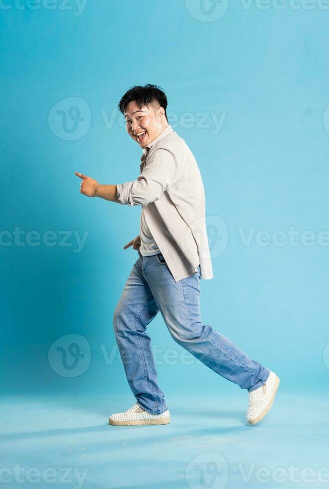 Full body image of Asian man posing on blue background photo