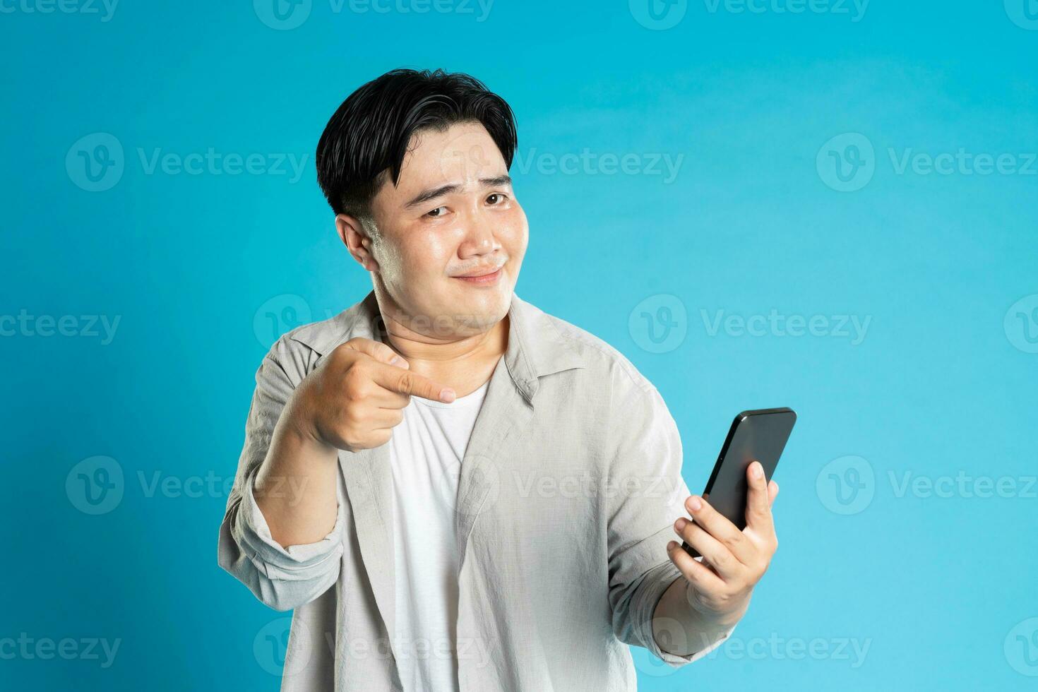 Image of Asian man using phone on blue background photo